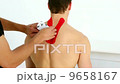 Physiotherapist applying red kinesio tape to patients back 9658167
