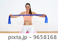 Fit model sitting on exercise ball stretching resistance band 9658168
