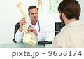 Doctor showing his patient a model of a spine 9658174