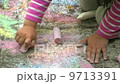 Child painting with chalk on the pavement 9713391