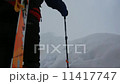 Ski mountaineer walking up along a steep snowy ridge with the skis in the backpack. In background a dramatic sky with a shiny bright sun. Ski mountaineer walking up along a steep snowy ridge with the skis in the backpack. In background a dramatic sky with a shiny bright sun. 11417747