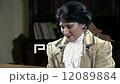 Upper body of woman dressed in 19th century clothes playing piano 12089884