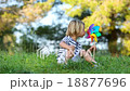 little boy in the park blowing colored pinwheel 18877696
