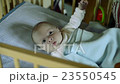Cute little baby boy lying in wooden crib, moving, 23550545