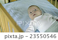 Cute little baby boy lying in wooden crib, moving, 23550546