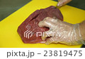 Cook Cuts a piece of Meat 23819475