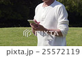 在清爽的陽光公園的草坪上，操作智能手機的高級男性的手 25572119