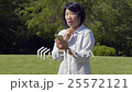操作有草坪的資深婦女一個智能手機在刷新的陽光公園 25572121