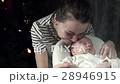 Mom with love looks at her baby, stroking his hand 28946915