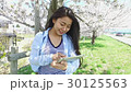 A woman using a tablet under a cherry tree 30125563