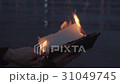 Young man reading burning book standing on coast 31049745
