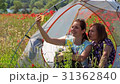 Laughing women in tent in poppy field make selfie 31362840