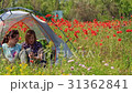 Women talk sitting in travel tent in poppy field 31362841