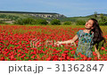 Woman with long hair enjoys poppy flower field 31362847
