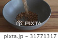 Raw grain buckwheat falling on rotating clay pot 31771317