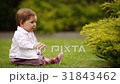 A cheerful baby-girl is sitting on the green grass 31843462