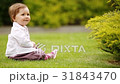 A cheerful baby-girl is sitting on the green grass 31843470