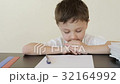 Sad little boy sitting at the table and doing home 32164992