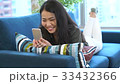 ソファーでスマホをいじりながらくつろぐ女性 33432366