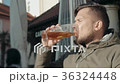Young Man Drinking Glass of Beer In a Street 36324448