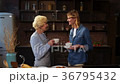 Cheerful elderly woman sharing cookies with her 36795432