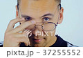 A young man is dressing glasses and looking at the 37255552
