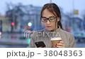 Young female uses her smartphone while drinking 38048363
