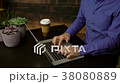 Man types on a laptop near a coffee 38080889