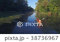 A female figure in a boat sails on a quiet river 38736967