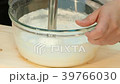 The cook whips the cheese mass with a blender. 39766030