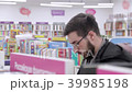 Young brunette black-haired man with glasses looking books on the bookshelves in the bookstore. 39985198