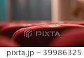 Close up backrest of red seats in a concert hall with a number plate and people in the background. 39986325