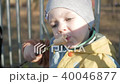 A pretty boy is eating a sausage outside. Cooked on fire bbq 40046877