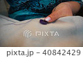 the hands of a middle-aged woman sew a button to the fabric 40842429