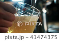 Bartender man is filling glass with beer in trendy bar indoors. 41474375