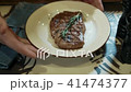 Waiter is putting plate with beef steak on table in restaurant. 41474377