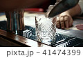 Close up of whisky glass being fulfilled with ice in stylish bar, slow motion. 41474399