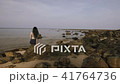 beautiful girl sits on rocks near sea shore and looks into distance. 41764736