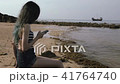 Young Tourist Girl Using Mobile Phone at the Beach near the Sea with Beautiful boat . 41764740