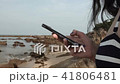 girl uses a mobile phone on the beach on the background of the sea and stones. writes a message. 41806481