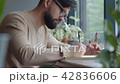 Modern man sits at the window in a cafe and writes in an a diary. 42836606
