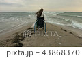 The disabled person gets out of the stroller on the shore of the sea 43868370