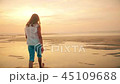Cute little ten year old blonde girl walking at beach near ocean at sunset 45109688
