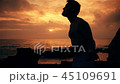 Silhouette of man exercising with a skipping rope on sunset background at ocean 45109691