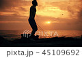 Silhouette of man exercising with a skipping rope on sunset background at ocean 45109692