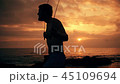 Silhouette of man exercising with a skipping rope on sunset background at ocean 45109694