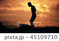 Silhouette of man exercising with a skipping rope on sunset background at ocean 45109710