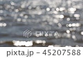 Mesmerizing bright defocused glares from the sun on the wavy surface of the water 45207588