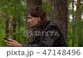 the guy is sitting with the phone in the woods 47148496