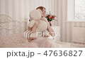 Blonde bride in negligee looks and hugs teddy bear 47636827